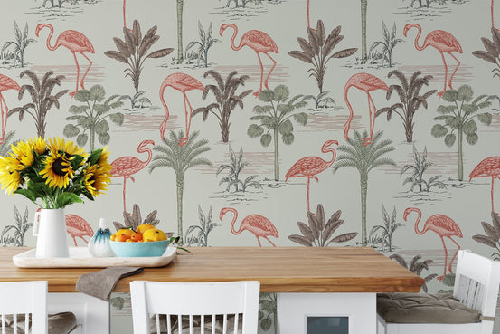 Dining room wall covered in pink flamingo and ink drawn palm tree wallpaper.