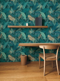 Palm leaves wallpaper on study area wall next to wooden crib and chair.