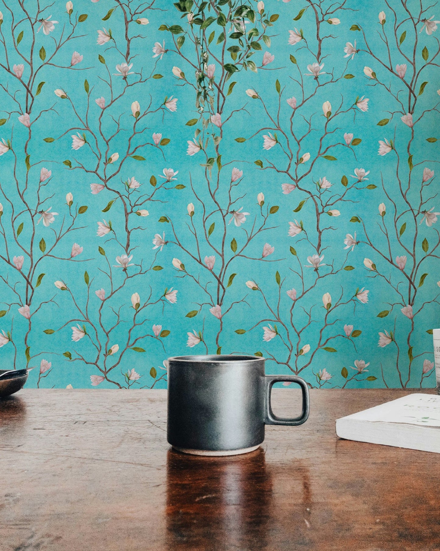 Chinoiserie magnolia wallpaper on a study wall with a dark coffee mug.