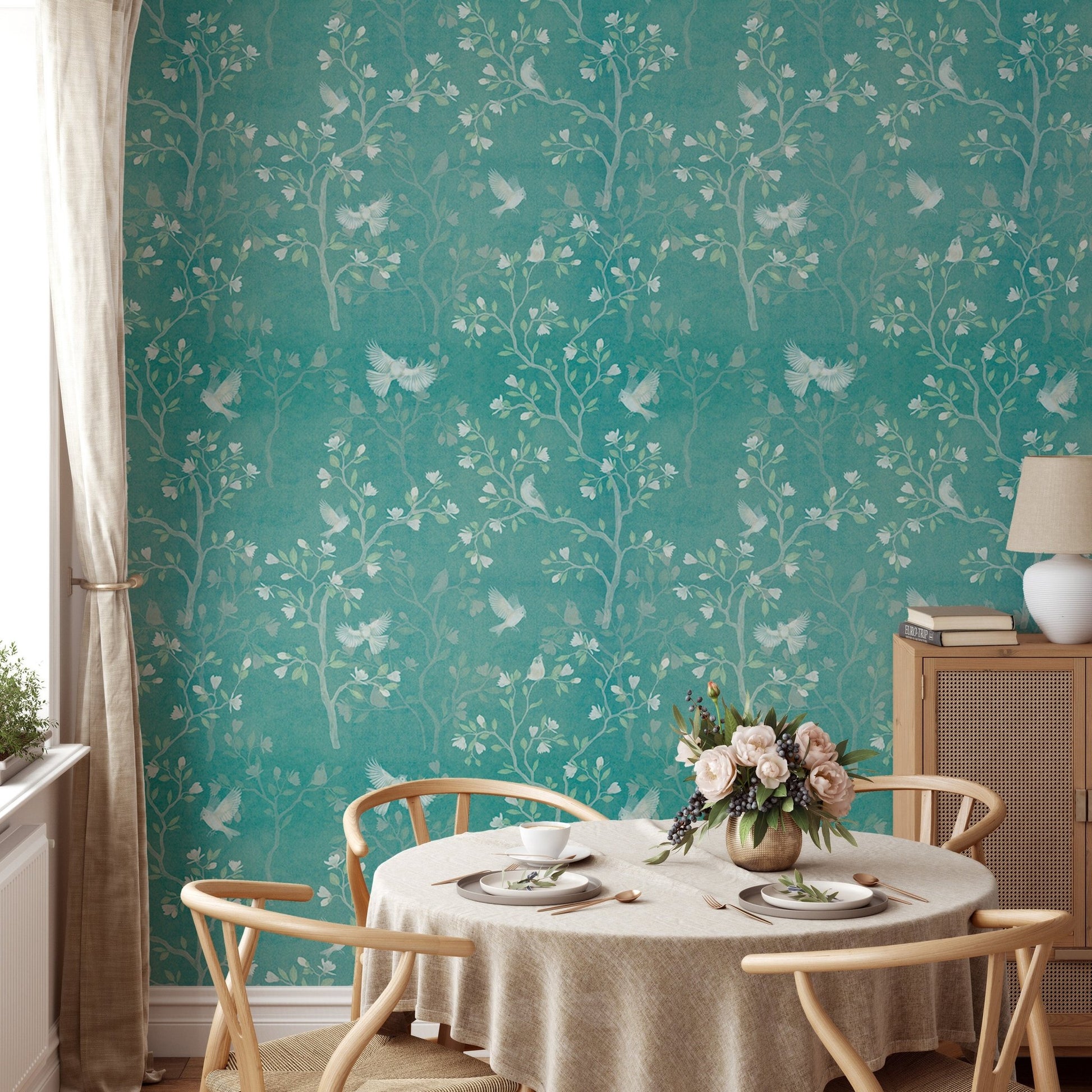 Magnolia tree wallpaper in a dining area with a round table and neutral chairs.