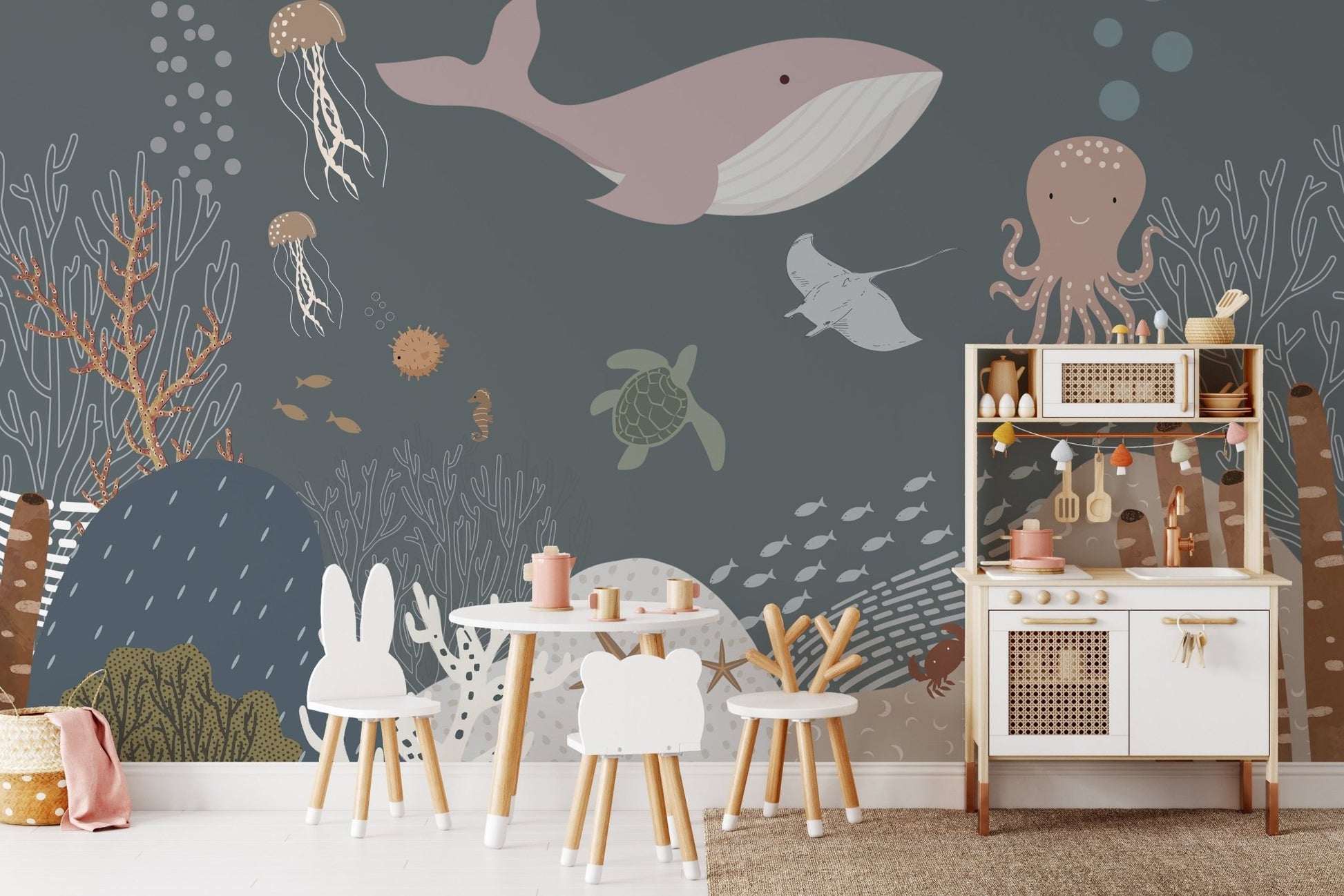 Hand-painted sea life wall mural behind a wooden play kitchen and table.