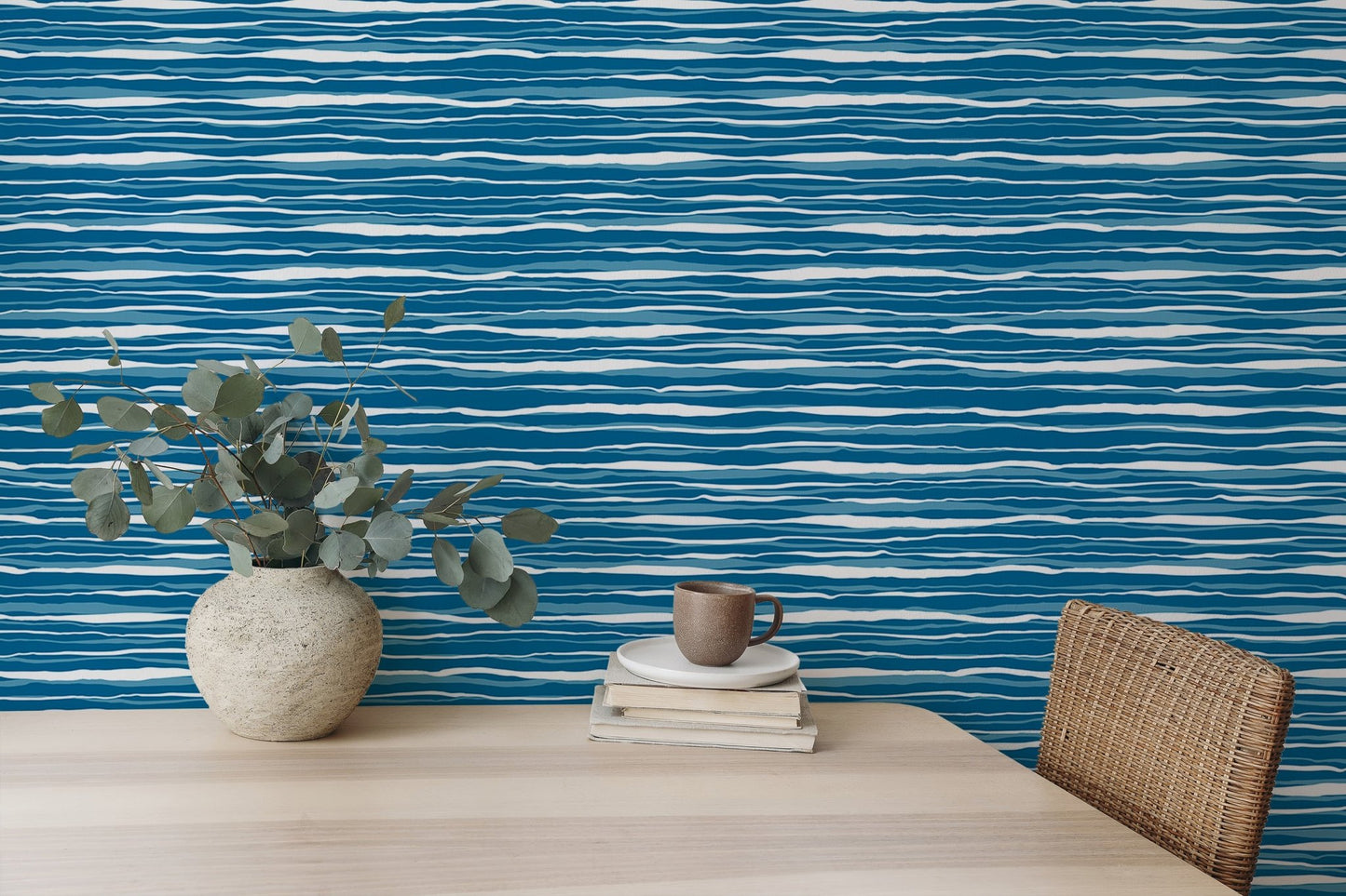 Minimalist desk setup featuring blue water stripes tile wallpaper and a vase.