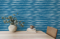 Minimalist desk setup featuring blue water stripes tile wallpaper and a vase.