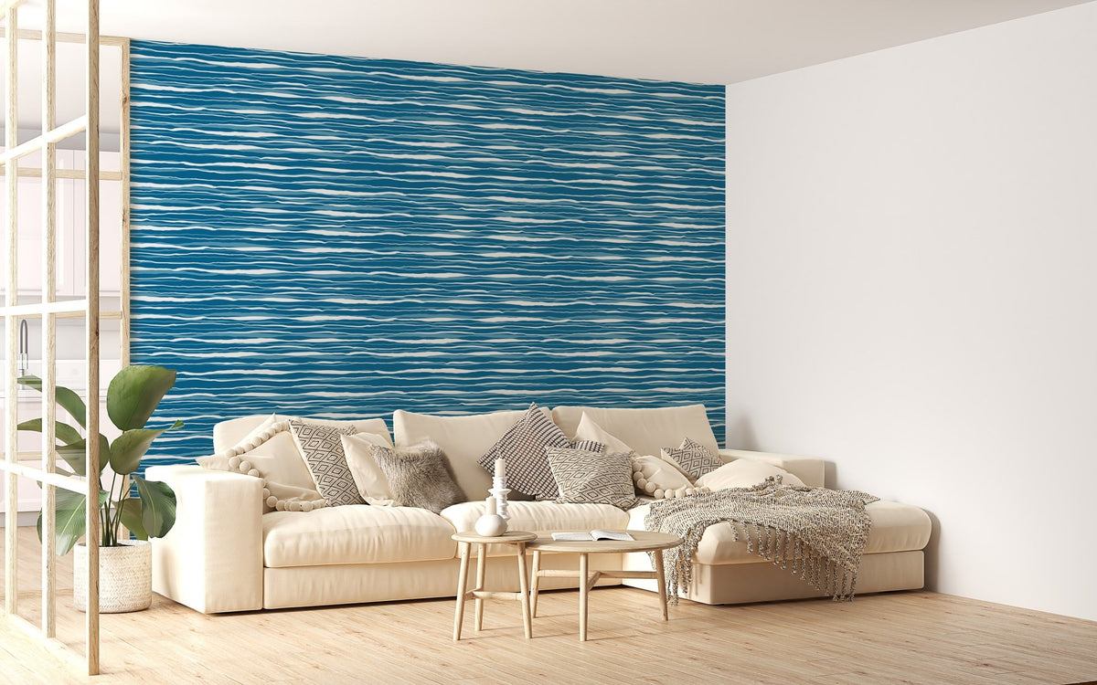 Blue ocean waves wallpaper on a living room wall behind a white sofa and green plant.