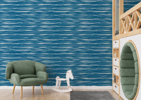 Hand drawn water stripes wallpaper in a kids play area with a green chair.