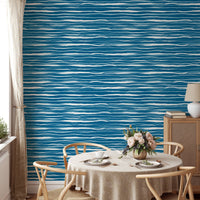 Circular dining table set against a blue water stripes tile wallpaper.