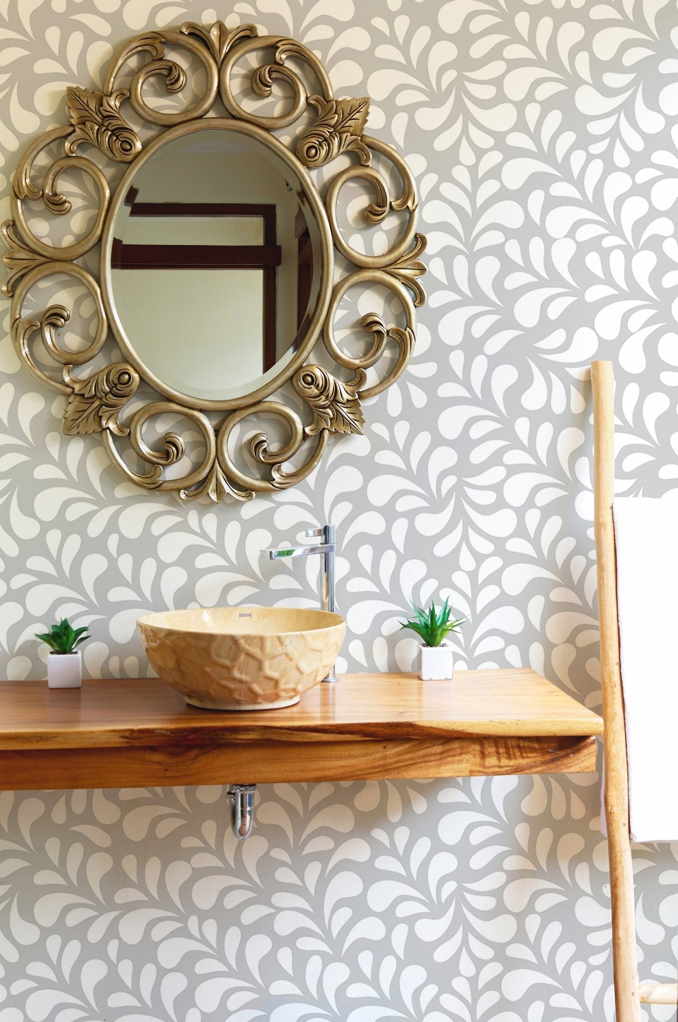 White drops damask wallpaper in a bathroom with a round gold mirror.