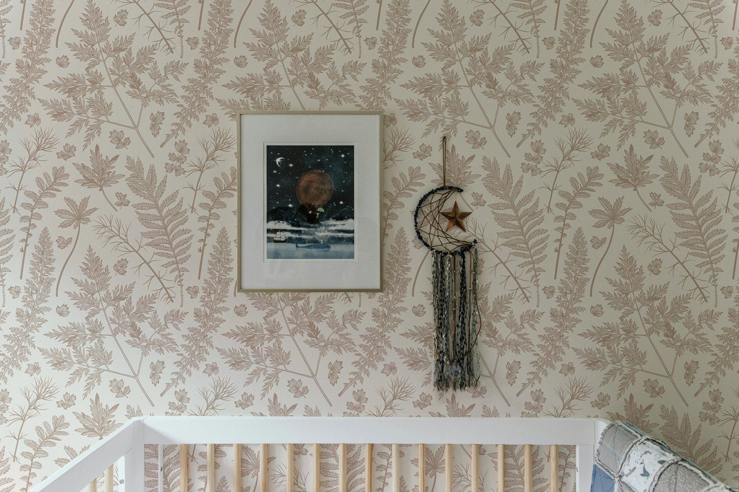 Botanical leaf pattern wallpaper installed above a white baby cot in a modern nursery.