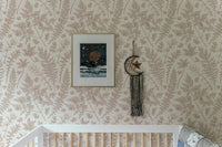 Botanical leaf pattern wallpaper installed above a white baby cot in a modern nursery.