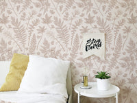 Pastel color leaves wallpaper on a bedroom wall with white pillows and yellow accents.
