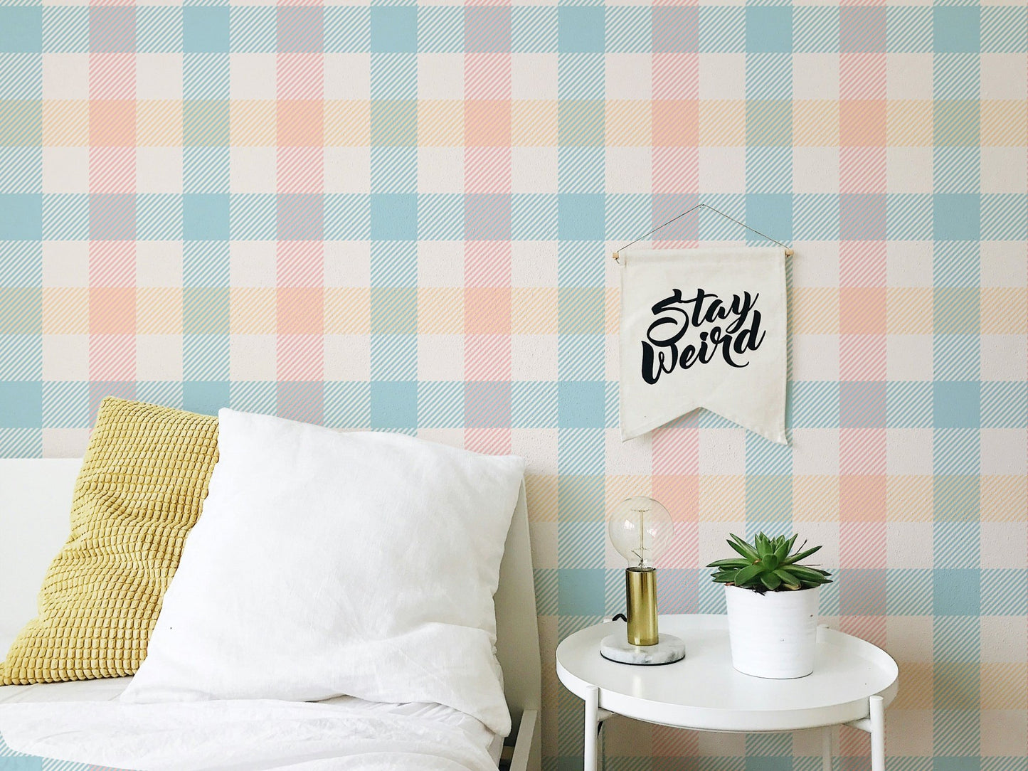 Blue and peach gingham wallpaper in a bedroom behind a white bed.