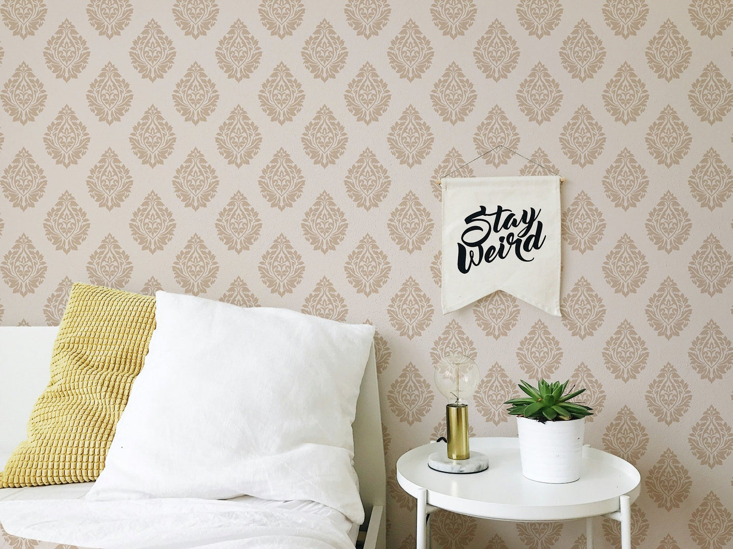 Brown Victorian wallpaper behind a bed with white and yellow pillows in bedroom.