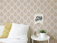 Brown Victorian wallpaper behind a bed with white and yellow pillows in bedroom.