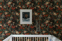 Dark botanical flower wallpaper installed above a baby crib in a neutral nursery.