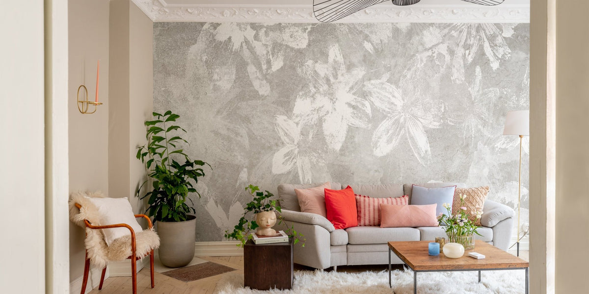 Grey botanical floral wallpaper mural behind a grey sofa in a bright living room.