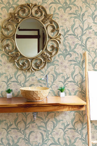 Ornate gold mirror hanging on a vintage flower green leaf wallpaper.