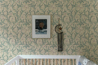 Crib in a room featuring sage green vintage floral print wallpaper.