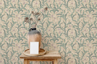 Vase with dried grass in front of green botanical leaf wallpaper.