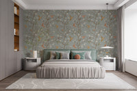 Sage green bird wallpaper behind a large bed with grey linens and white lamps.