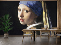Artistic portrait wall mural behind a wooden dining table and green potted plant.