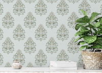 Potted plant on a white shelf with green damask wallpaper background.
