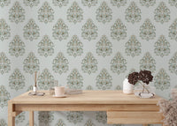 Minimalist office space with a wooden desk against green damask wallpaper.