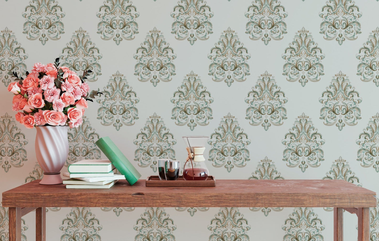 Green damask wallpaper on a study wall with a wooden desk and pink flowers.