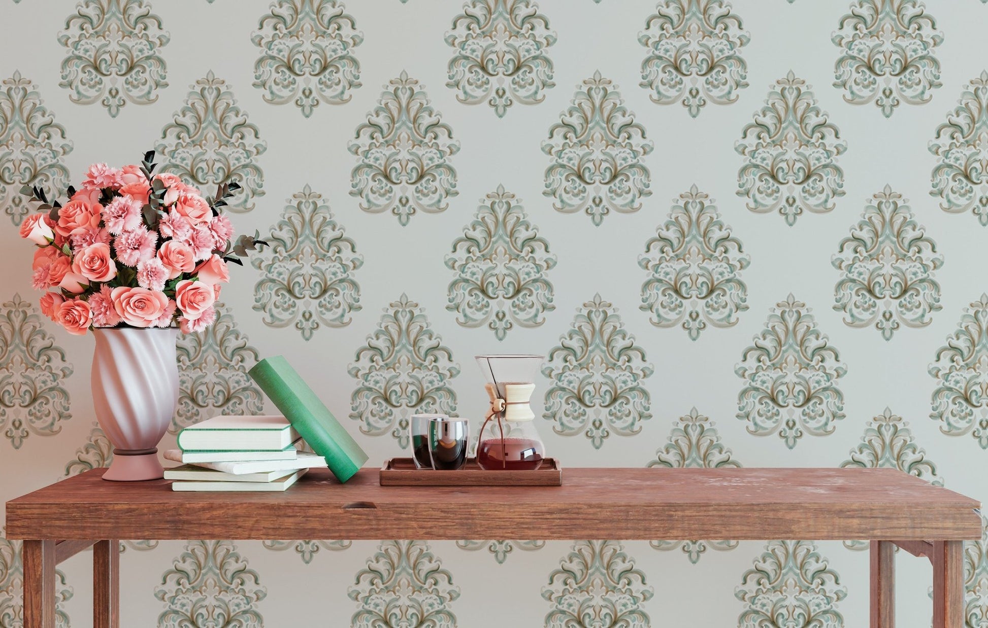Green damask wallpaper on a study wall with a wooden desk and pink flowers.