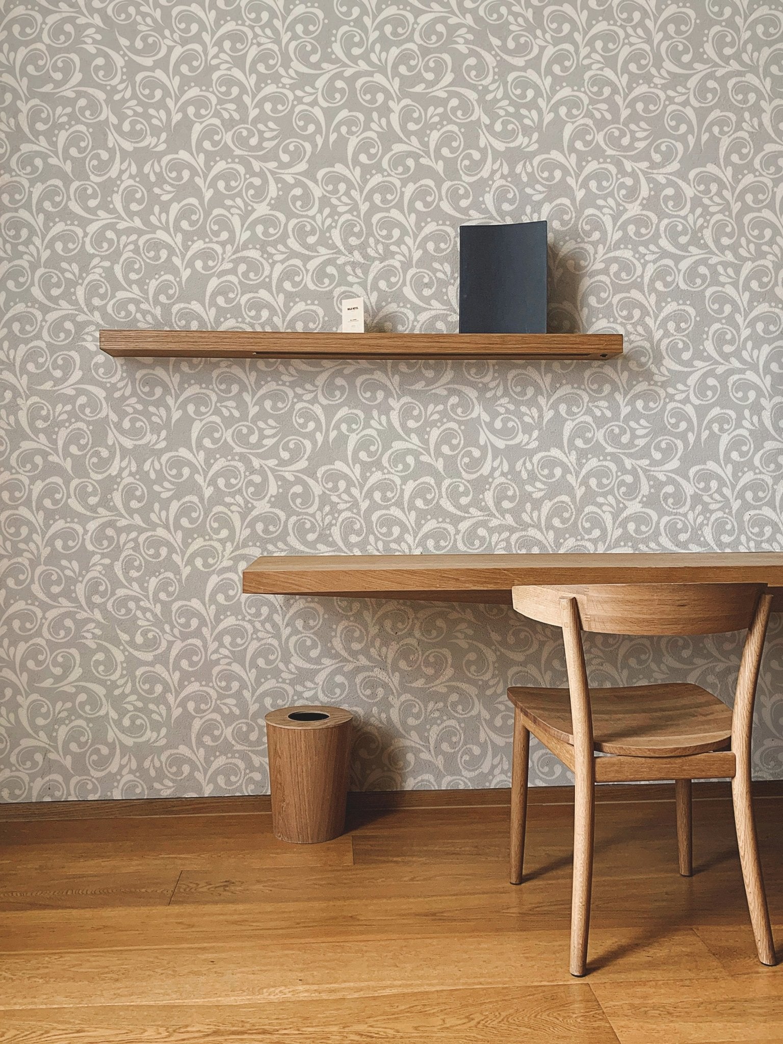 Vintage royal elegant damask pattern wallpaper behind a wooden desk and chair.