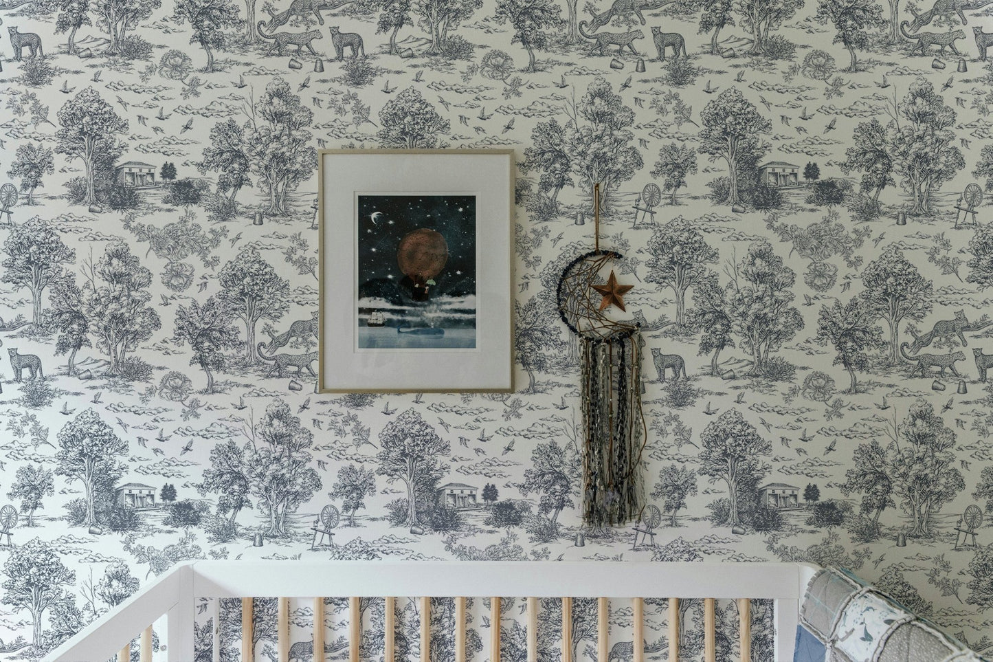 Toile de Jouy style wallpaper in a nursery room with a white crib.