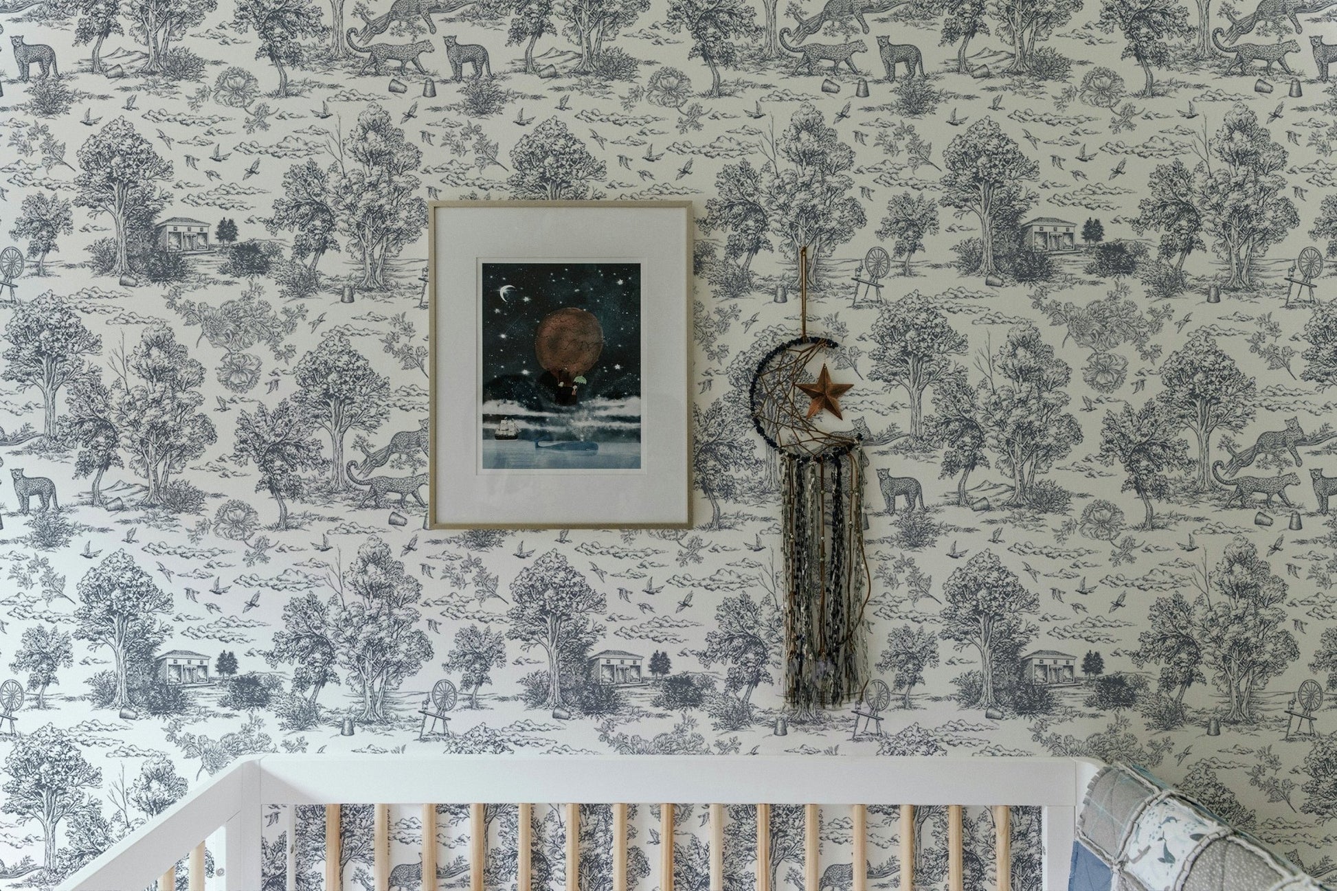Toile de Jouy style wallpaper in a nursery room with a white crib.