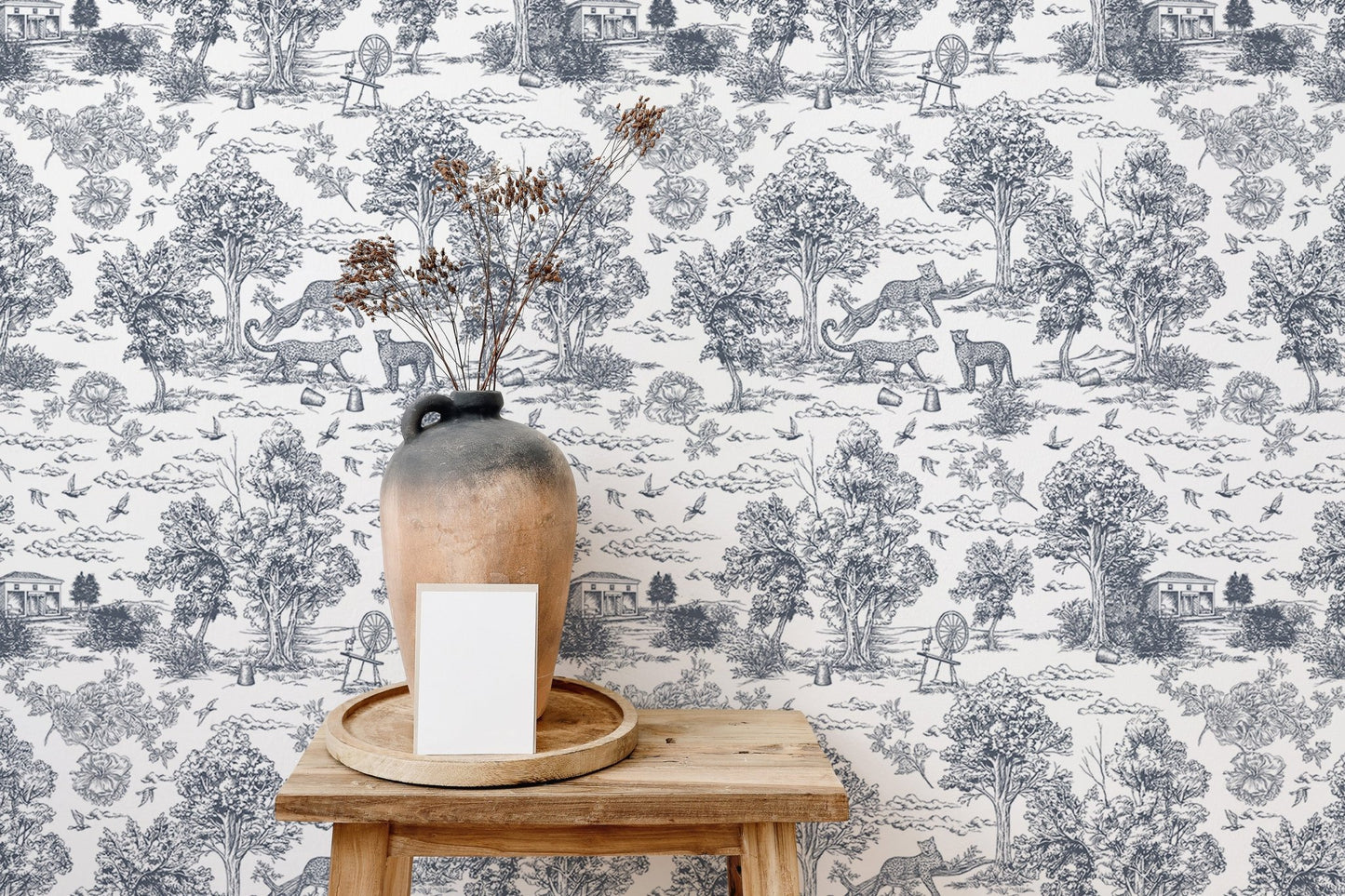 Grey and white tree pattern wallpaper behind a wooden stool and ceramic vase.