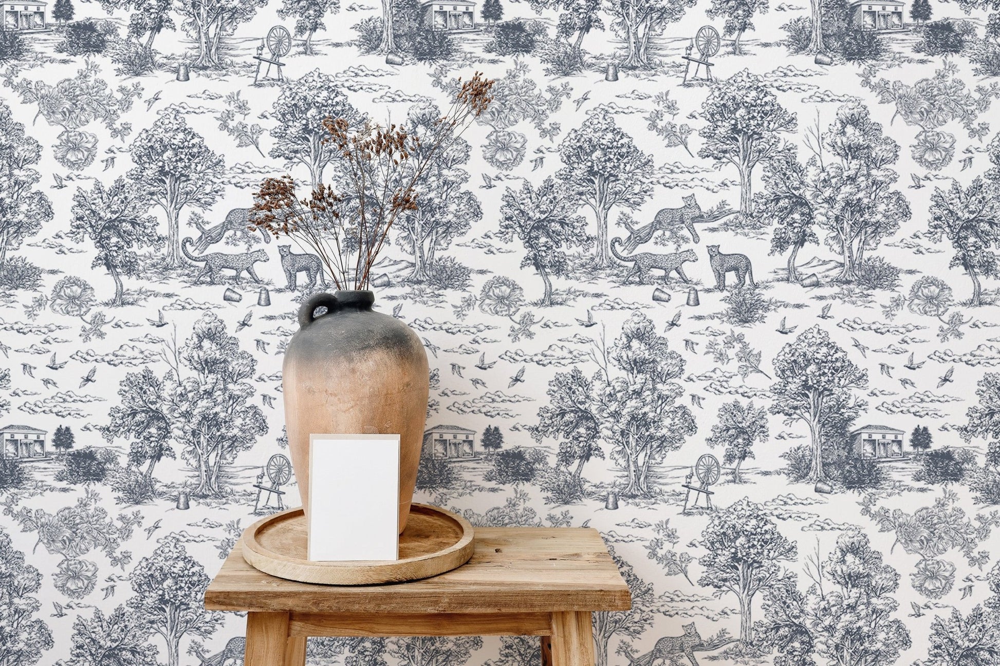 Grey and white tree pattern wallpaper behind a wooden stool and ceramic vase.