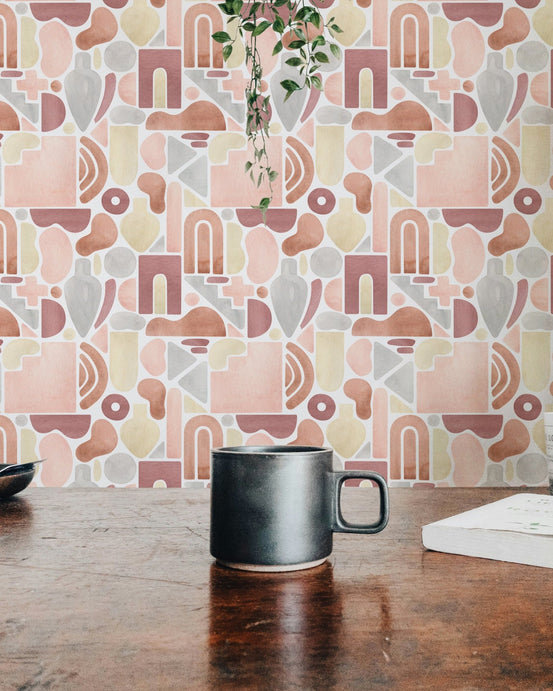 Dining space wallpaper with abstract patterns behind a dark wood table and ceramic mug.