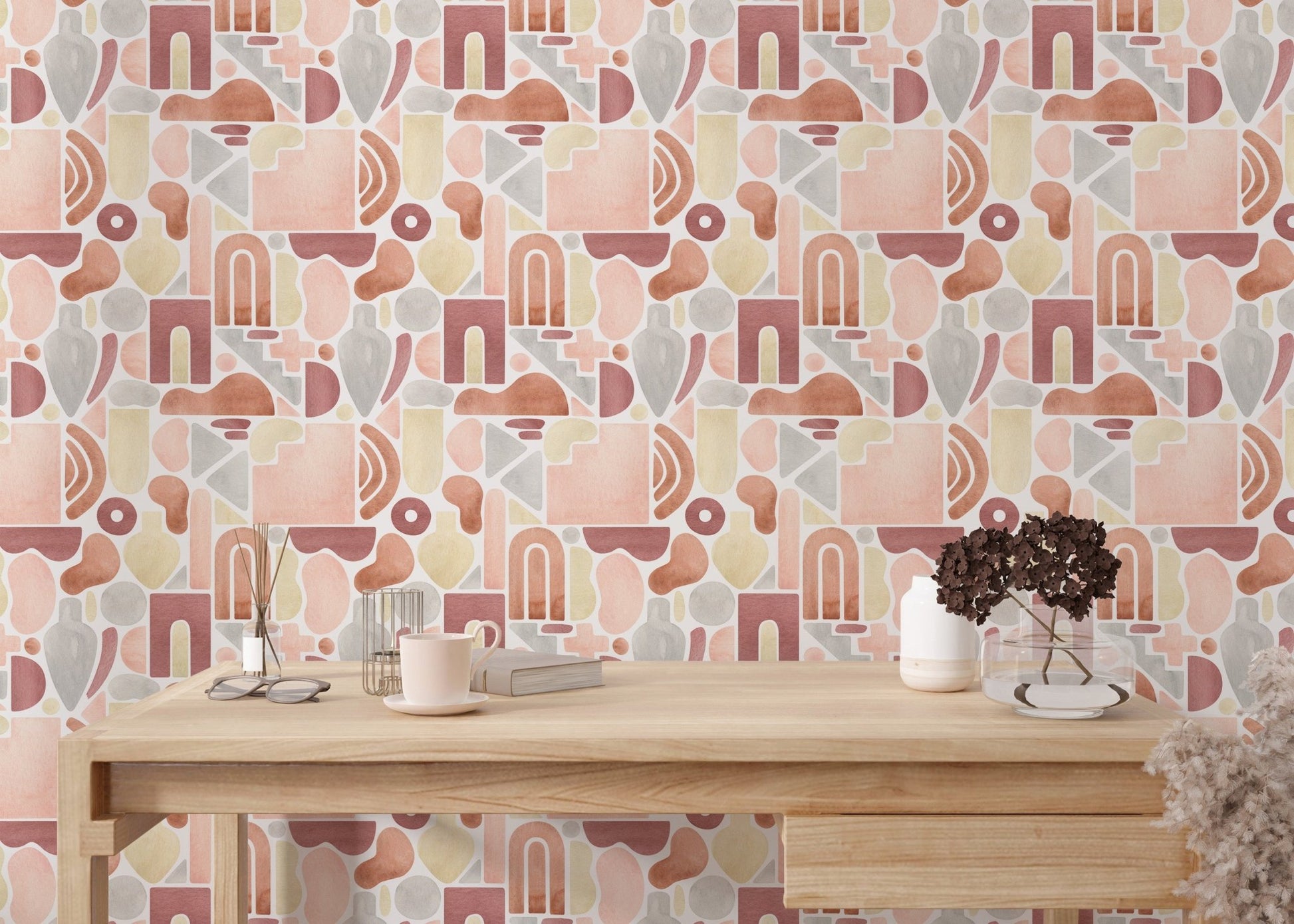 Home office setup with geometric abstract wallpaper behind a light oak desk and white chair.