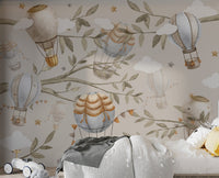 Watercolor hot air balloons with festive flags floating among branches and leaves on a beige background.