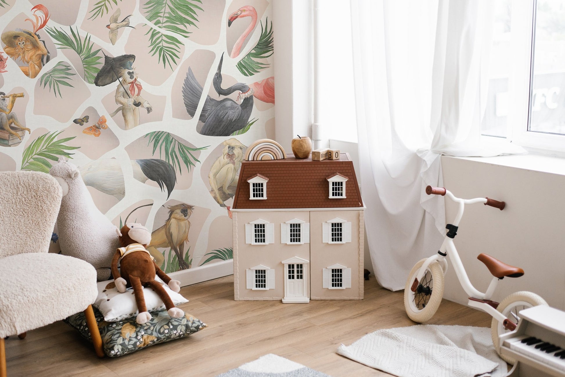 Nursery wall mural showing monkeys and a toy house on light wood floors.