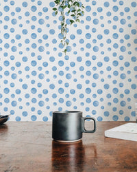 Dark mug on a wooden table with a blue polka dot wallpaper background.