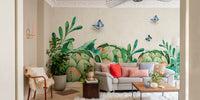 Living room featuring watercolor greenery wall mural and grey sofa.