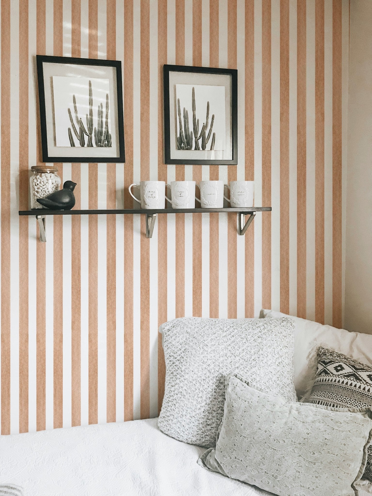 Vintage brown striped wallpaper behind a pillow and frame. 
