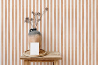 Striped watercolor wallpaper behind wooden table and vase