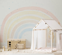 Pastel rainbow design wall mural behind white wooden play house for children