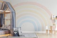 Large rainbow wall mural in nursery with wooden tiny bed and table