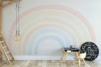 Watercolor rainbow wall mural in study space with small wooden chair and desk