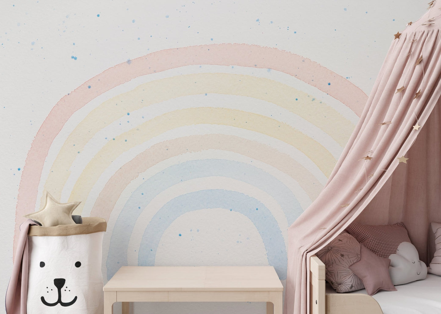 Rainbow wall mural behind pink bed canopy and toy storage bin