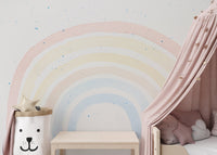 Rainbow wall mural behind pink bed canopy and toy storage bin