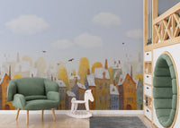 Nursery wall mural featuring a soft blue sky and pastel city house illustrations.
