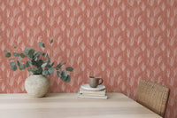 Desk area with terracotta botanical wallpaper and green potted plant.