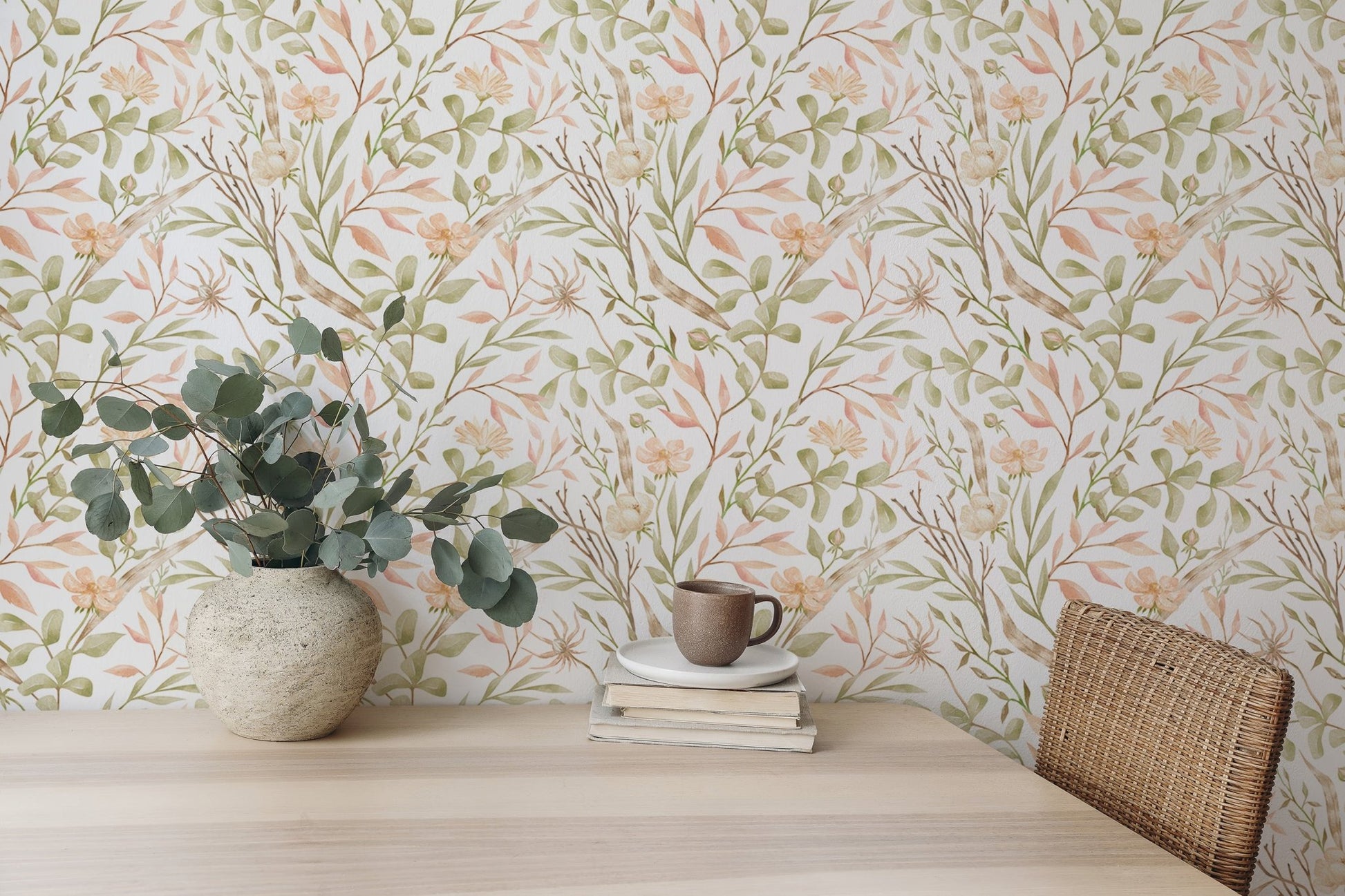 Botanical leaf print wallpaper behind a desk with a ceramic vase and eucalyptus.