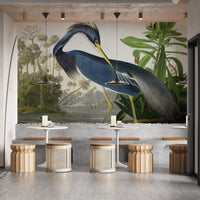 Botanical heron wall mural in a cafe setting with wooden stools and small tables.